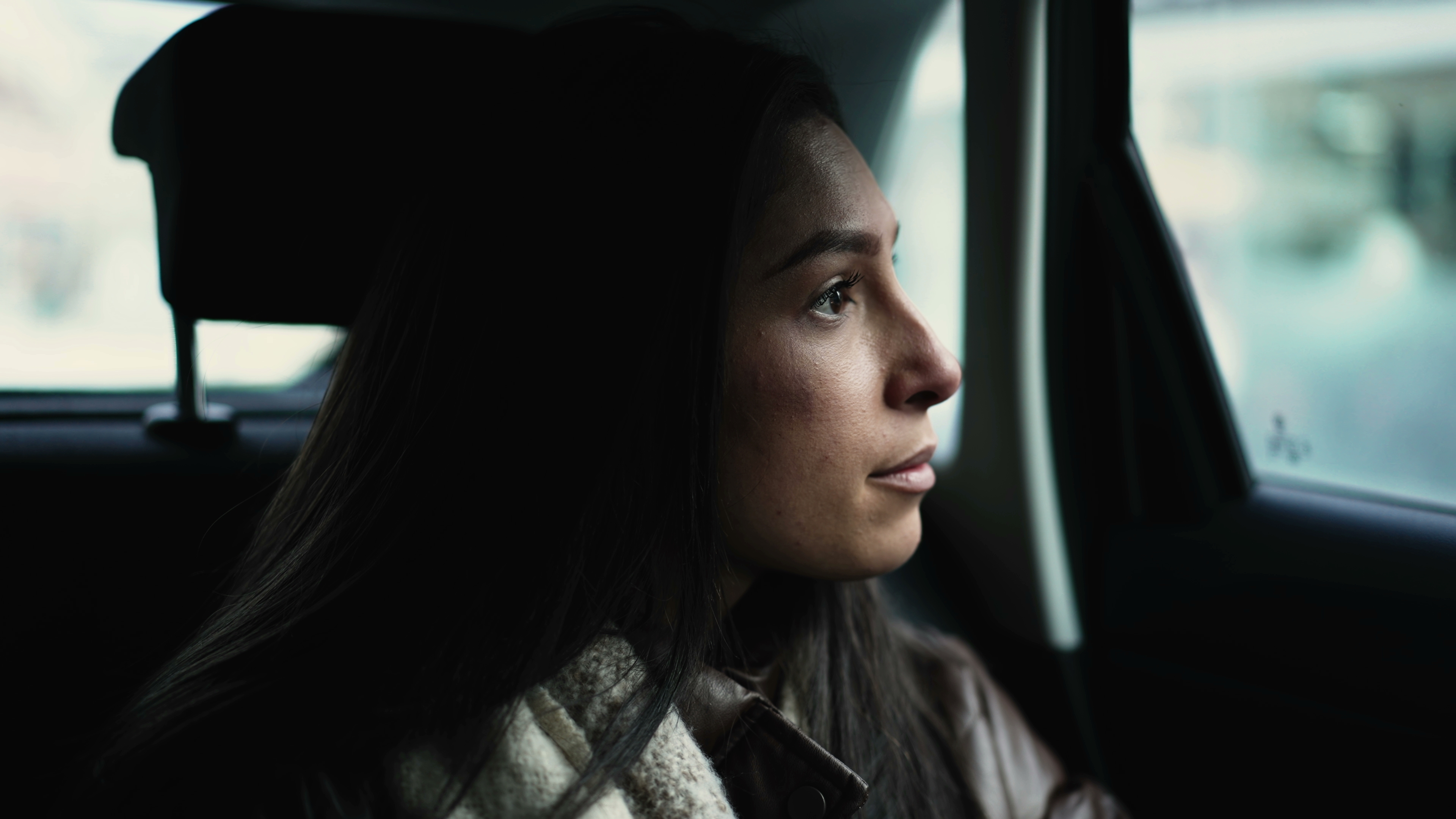 Female passenger inside car backseat looks out window. | Source: Shutterstock